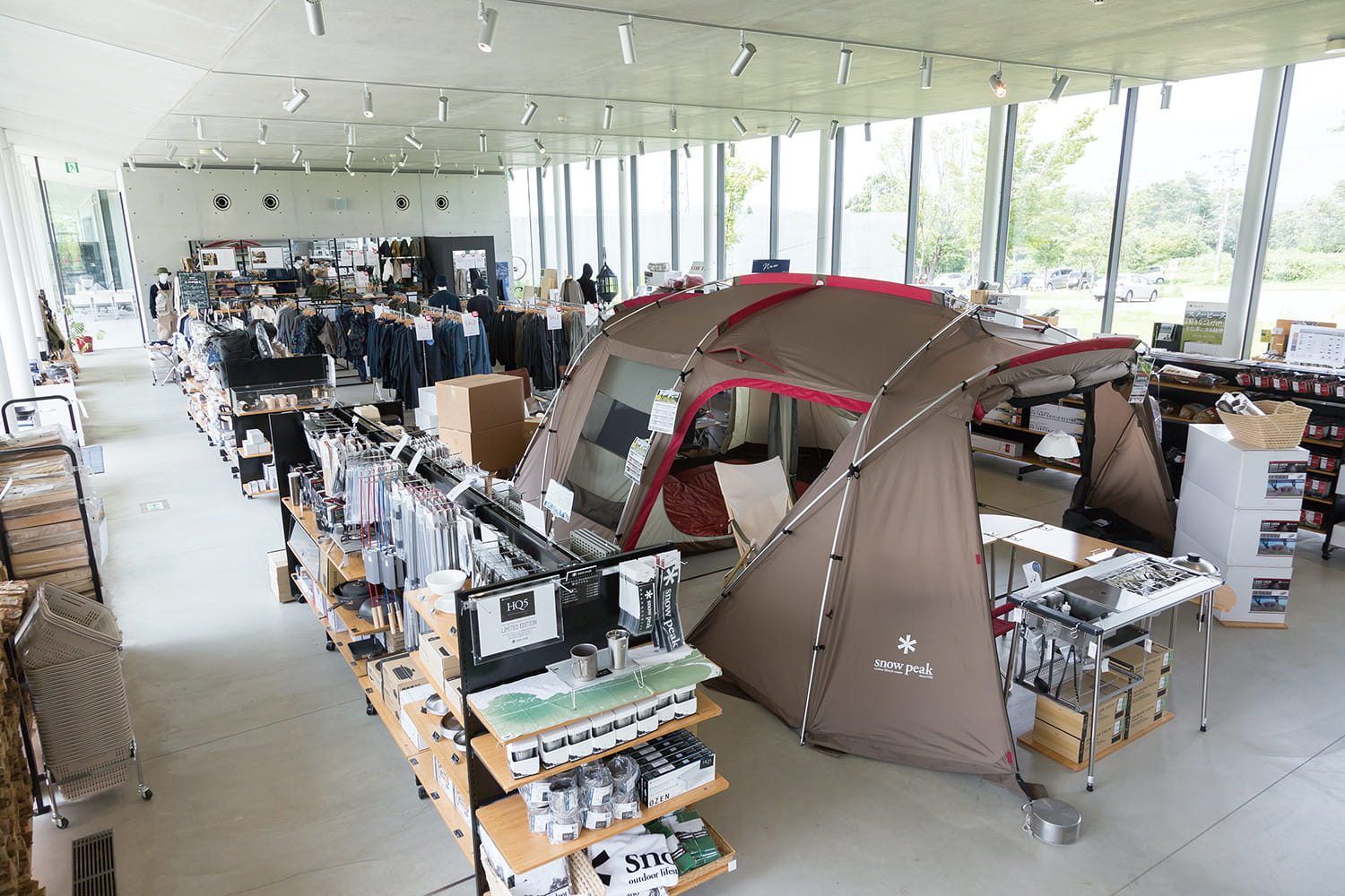 Ảnh 18 · HEADQUARTERS Store: lều dựng thật giữa cửa hàng, bán cả củi và đá — showroom sống. Nguồn: snowpeak.co.jp